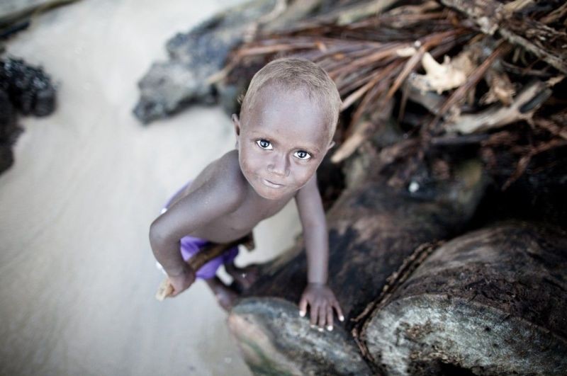 A young boy climbs driftwood on Tetapare.